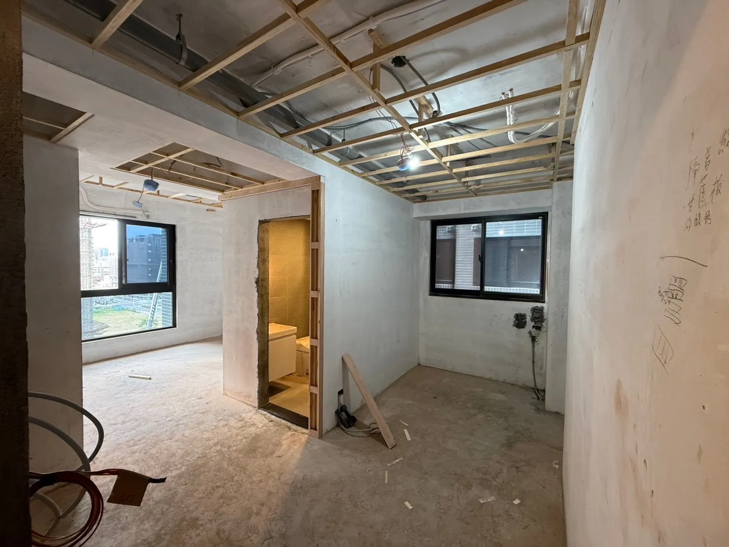 住宅裝潢施工中，空間結構與浴室隔間已初步成形，天花板進行木作骨架施作。此階段為設計公司統籌工班的裝潢流程示意，強調專業設計師監控能確保動線與結構規劃更精準。