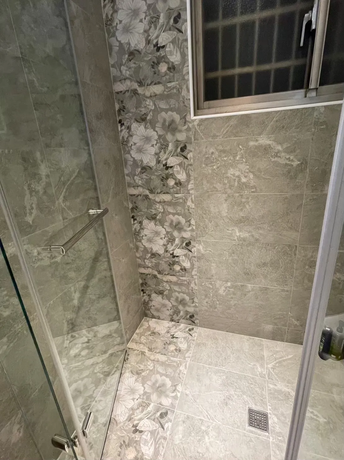 現代衛浴空間設計，主牆面採用花磚作為視覺亮點，其餘牆面選擇素色磁磚，透過重點材質配置方式，有效控制裝潢預算並提升整體質感。