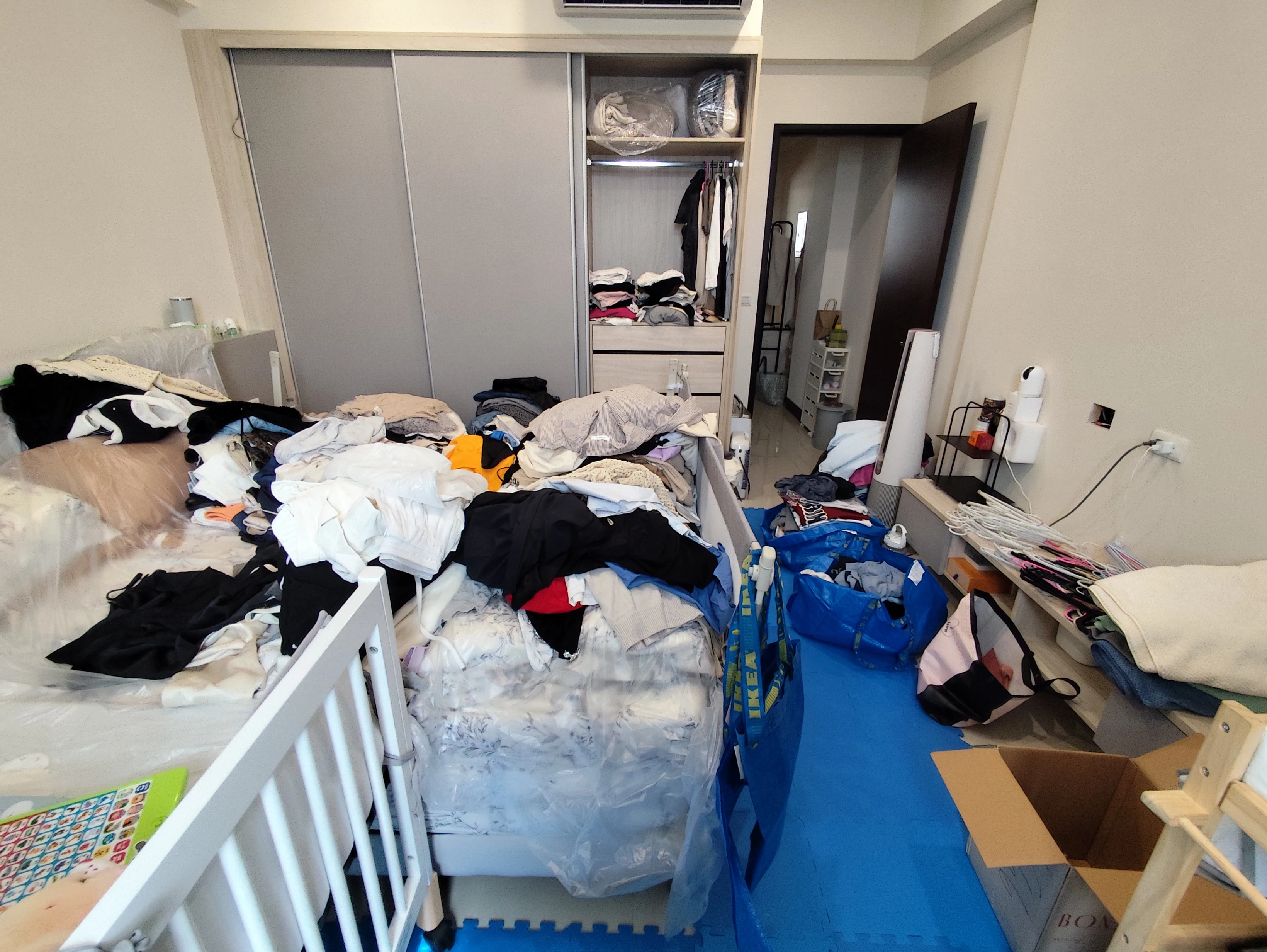 台中神岡案例05，臥室整理前，床面與周邊擺放衣物及袋裝物品
