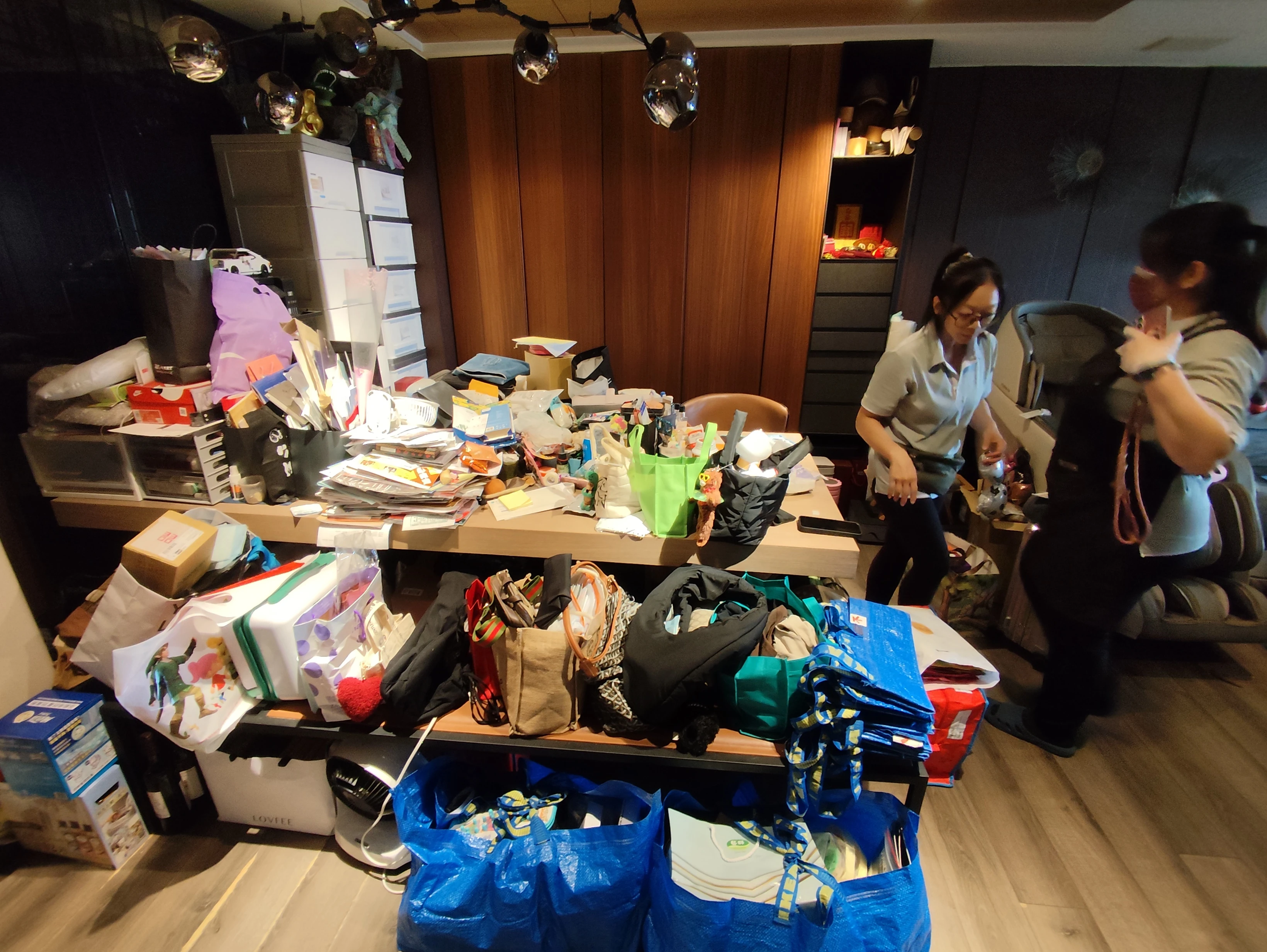 台中西屯客廳整理前，長桌與壁櫃前方堆放生活物品及箱袋
